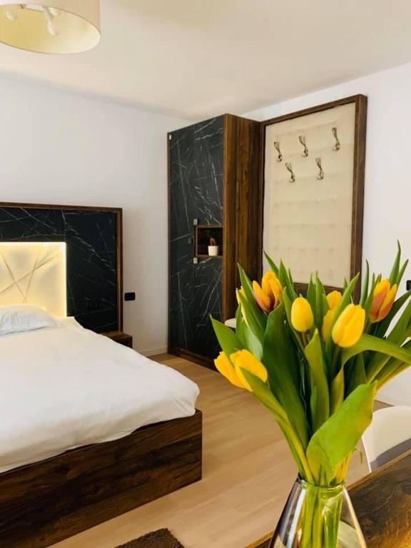 a bedroom with a bed and a vase with yellow flowers at Valea Putnei Residence- Rooms for rent in Valea Putnei