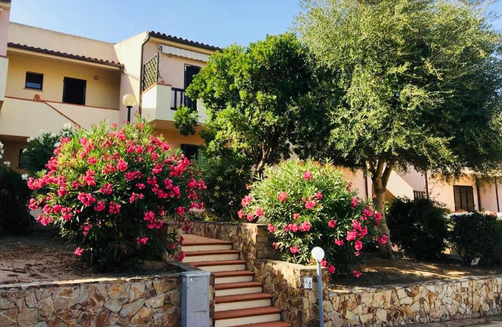 uma casa com flores cor-de-rosa e uma parede de pedra em Le residenze Itaca em Porto Pozzo