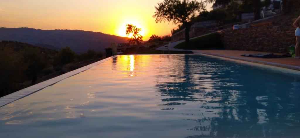 a swimming pool with the sunset in the background at Casa Nova Velha in Seixas