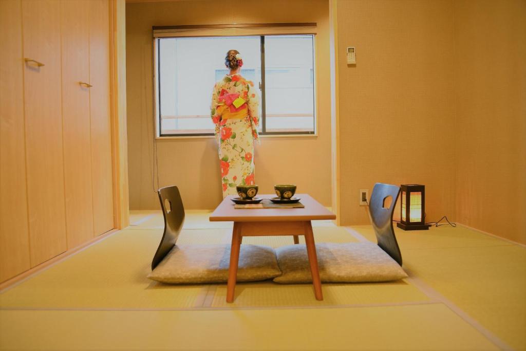 a woman in a kimono standing in a room at Kamozen Kyoto Machiya Stay in Kyoto