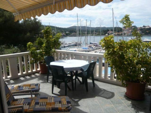 a table and chairs on a balcony with a view of a harbor at The Olive Tree in Lumbarda