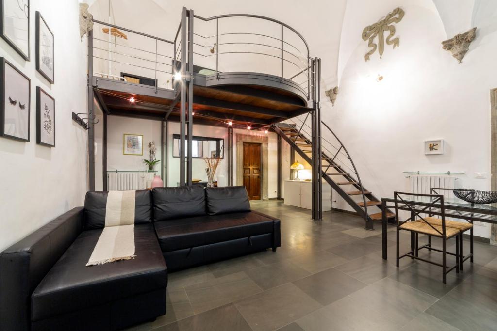 sala de estar con sofá negro y escalera de caracol en Pepi loft in a historical building, en Florencia