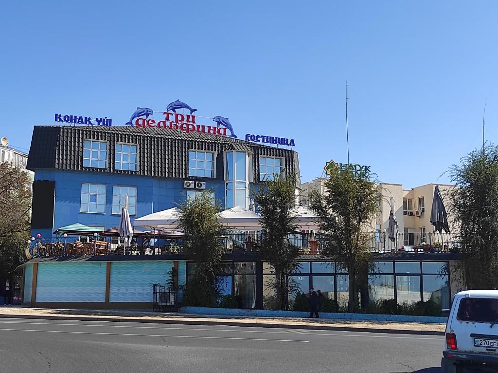 a building with a restaurant on the side of a street at Three Dolphins Hotel in Aktau