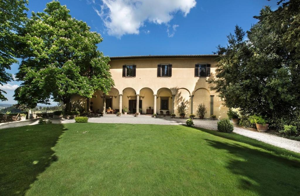 une grande maison avec une grande pelouse devant elle dans l'établissement Villa Il Poggiale Dimora Storica, à San Casciano in Val di Pesa