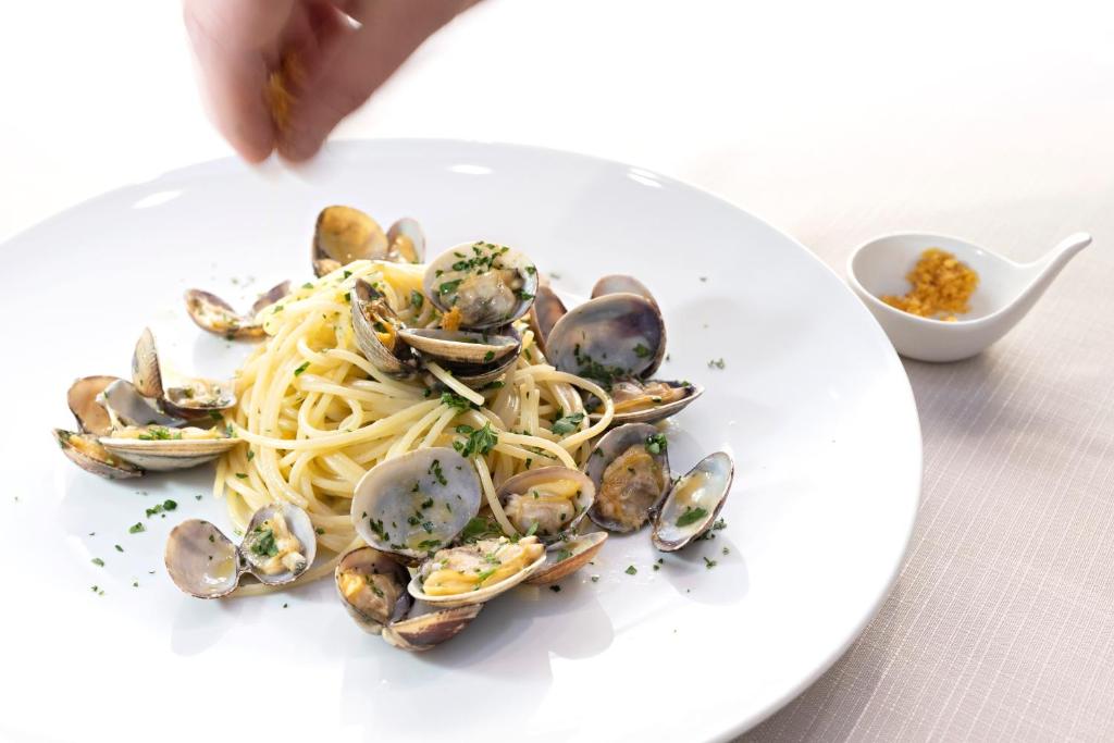a plate of pasta and clams on a table at Hotel Mirage in Viareggio