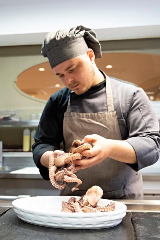 a man in a kitchen preparing food on a plate at Hotel Mirage in Viareggio
