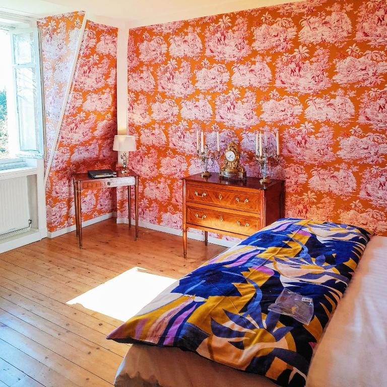 a bedroom with a bed and a dresser and pink wallpaper at Chateau de Hiéville in Hiéville