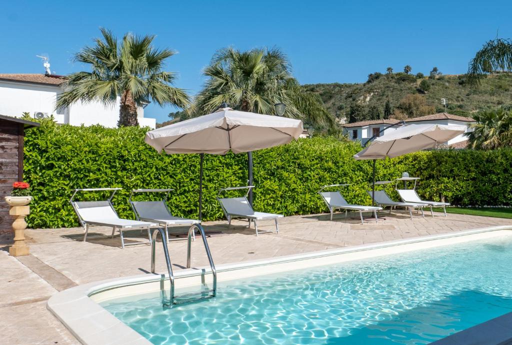 una piscina con sillas y sombrillas y una piscina en Deluxe Sicily Villa, en Buonfornello