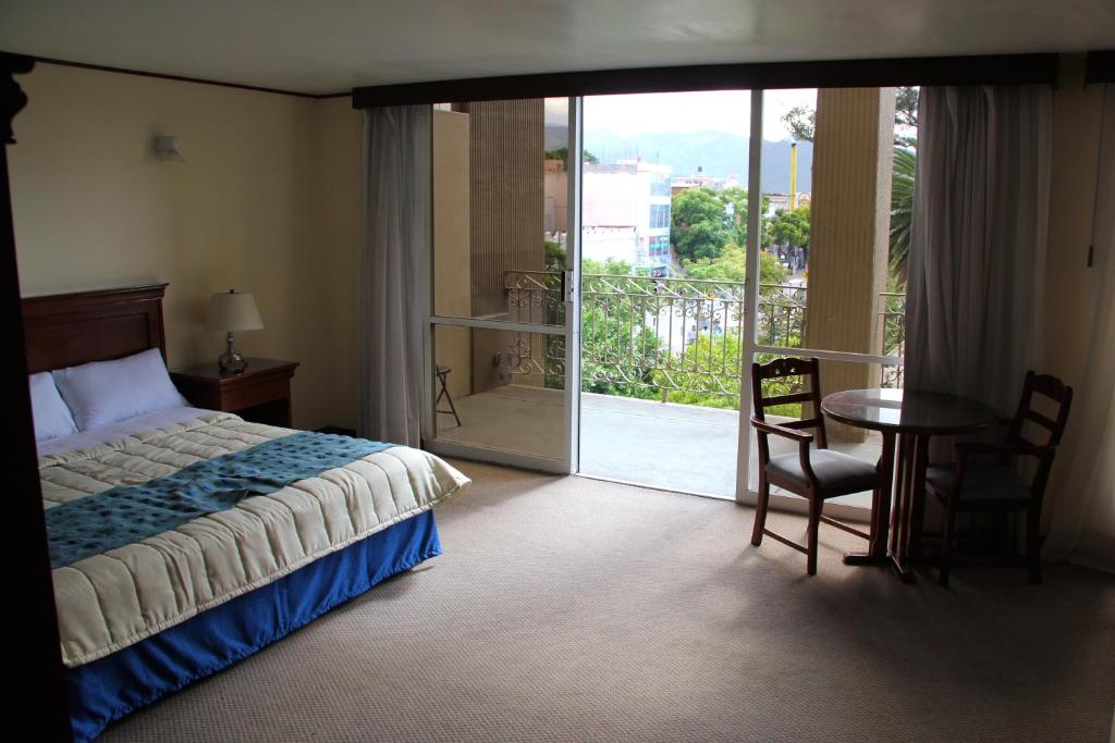 a bedroom with a bed and a table and a balcony at Hotel Tehuacan Plaza in Tehuacán