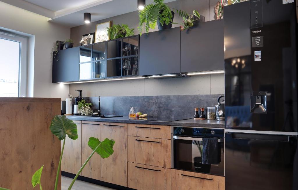 - une cuisine avec des placards en bois et un réfrigérateur noir dans l'établissement Loft Apartament Patio Vita- Klimatyzacja Garaż podziemny, à Kielce
