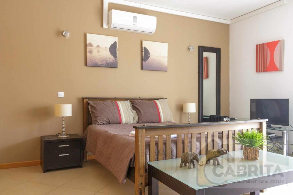 um quarto com uma cama e um berço e uma televisão em Estudio GardenMar Cabanas Gardens by Your Home Algarve em Cabanas de Tavira