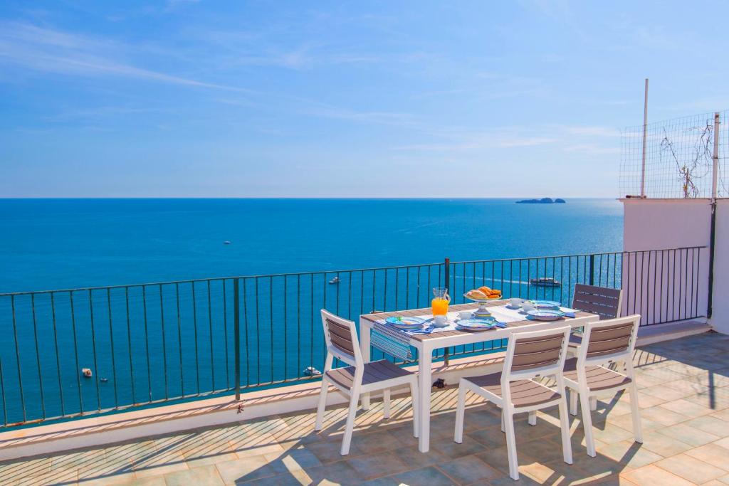 uma mesa e cadeiras numa varanda com o oceano em Estate4home - Maison Jenny em Positano