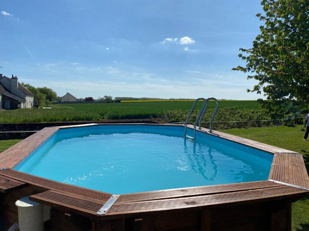 a swimming pool with a wooden deck around it at Le Maquis in Charmes