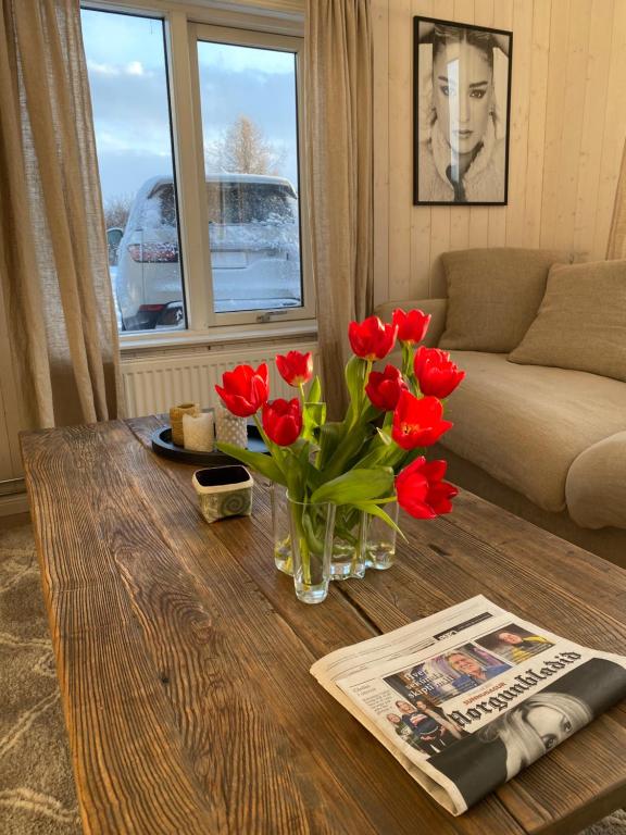 una sala de estar con un jarrón de flores rojas sobre una mesa en A three bedroom cabin with a hot tub, en Selfoss