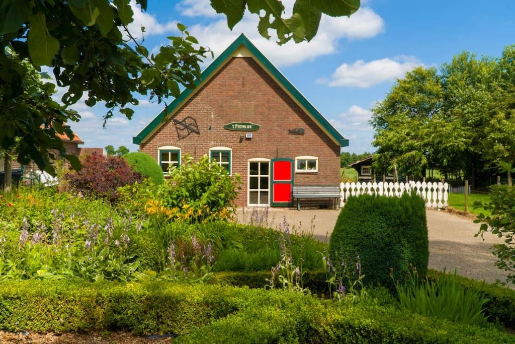 une maison avec une porte rouge et une clôture blanche dans l'établissement Pothuus 2 persoons vrijstaand huis met vrij uitzicht in de Achterhoek, à Ruurlo