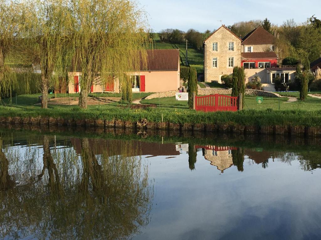 a house with a red fence next to a river at Calme au Canal de Centre in Dennevy