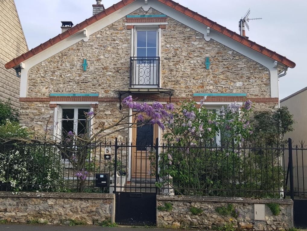 a stone house with a gate and purple flowers at Le Vieux Tilleul in Vaires-sur-Marne