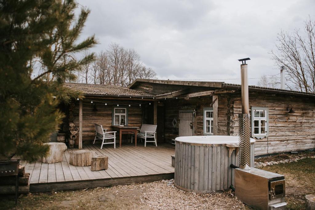 a log cabin with a deck with a table and chairs at Vienkiemio Oazė - Namelis Prie Šermukšnio in Galvokai