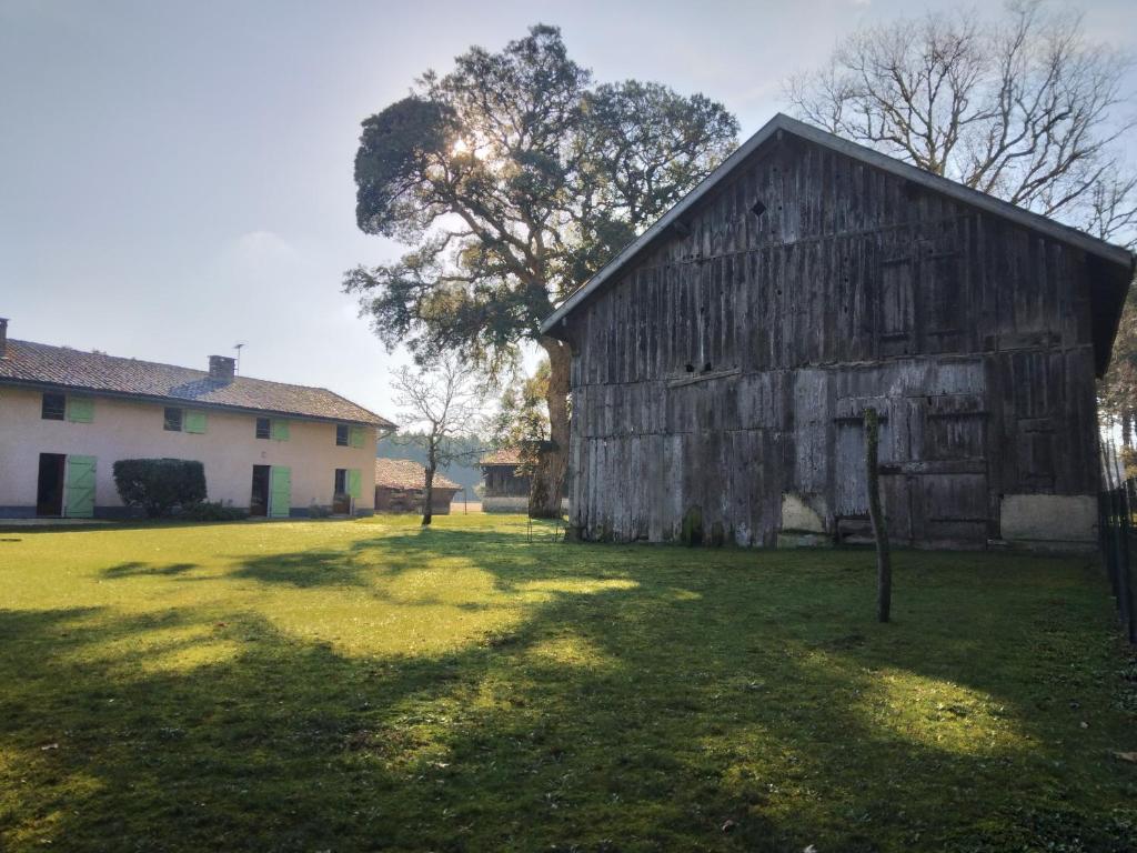 un antiguo granero sentado en un campo junto a una casa en LE PETIT FROUAS CENTRE en Vielle-Saint-Girons