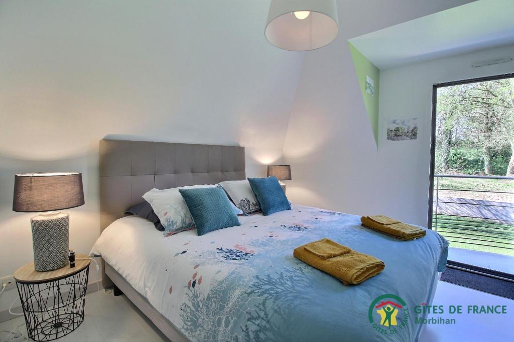 een slaapkamer met een bed met blauwe kussens en een raam bij VILLA LE NID BRETON in Bignan