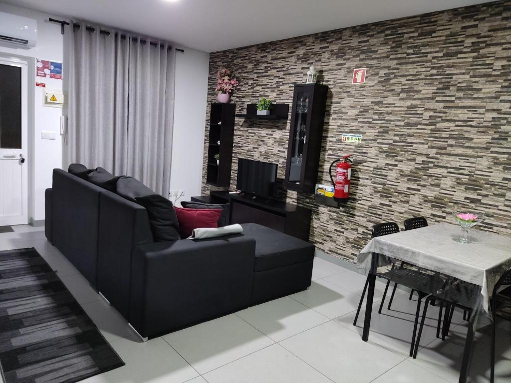 ein Wohnzimmer mit einem schwarzen Sofa und einem Tisch in der Unterkunft Casa de férias e fins de semana,1 in Esposende