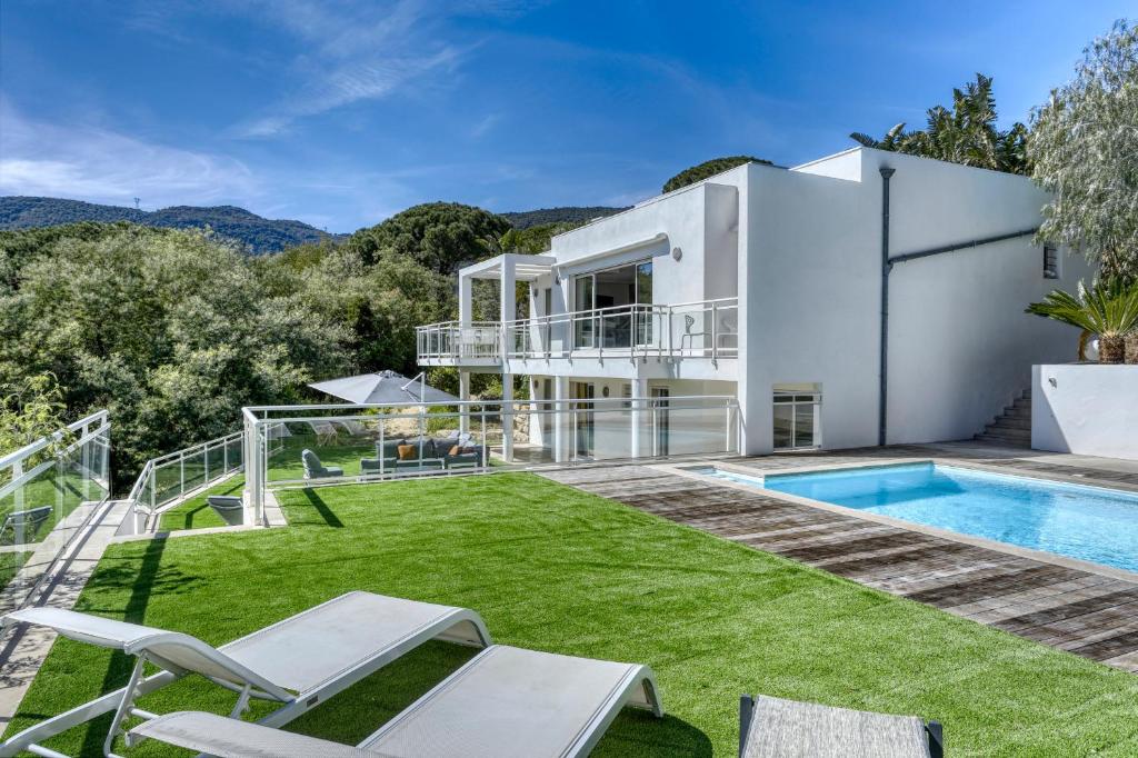 uma villa com uma piscina e um quintal em Beautiful contemporary villa with sea view, heated swimming pool, near Saint Tropez em Cavalaire-sur-Mer