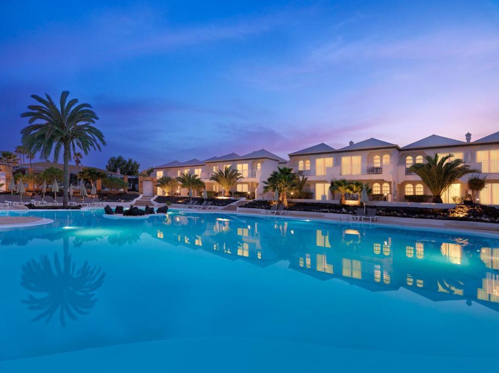 a large swimming pool in a resort at night at H10 Ocean Suites in Corralejo