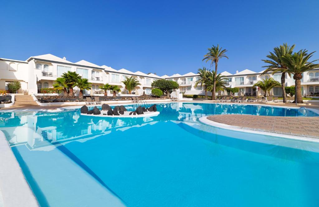 una gran piscina con palmeras y edificios en H10 Ocean Suites en Corralejo