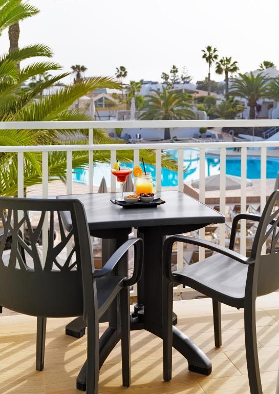 a black table and chairs on a balcony with a pool at H10 Ocean Suites in Corralejo