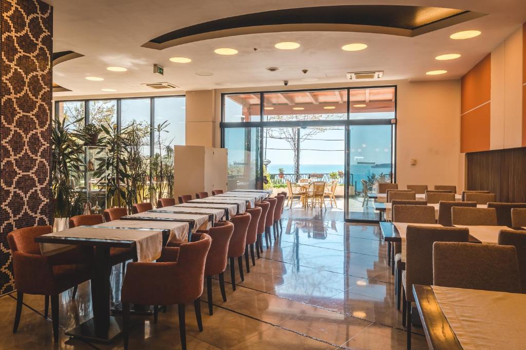 a row of tables and chairs in a room with windows at Hotel & Apartments HEC Residence in Sveti Stefan