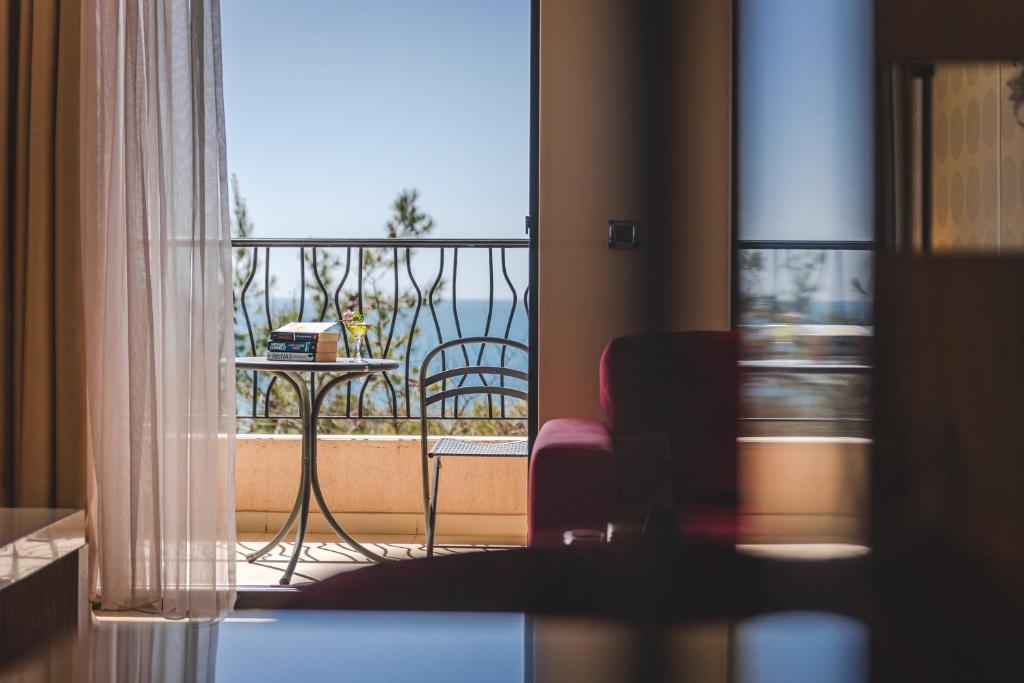 a room with a balcony with a view of the ocean at Hotel & Apartments HEC Residence in Sveti Stefan