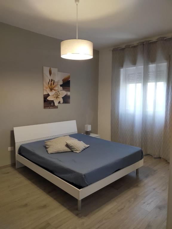 sypialnia z łóżkiem z niebieskim materacem i oknem w obiekcie Casa Punta d'Oro w mieście Faccia di Trippa