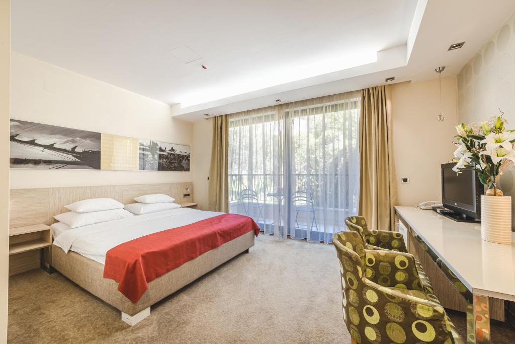 a bedroom with a bed and a desk and a television at Hotel & Apartments HEC Residence in Sveti Stefan