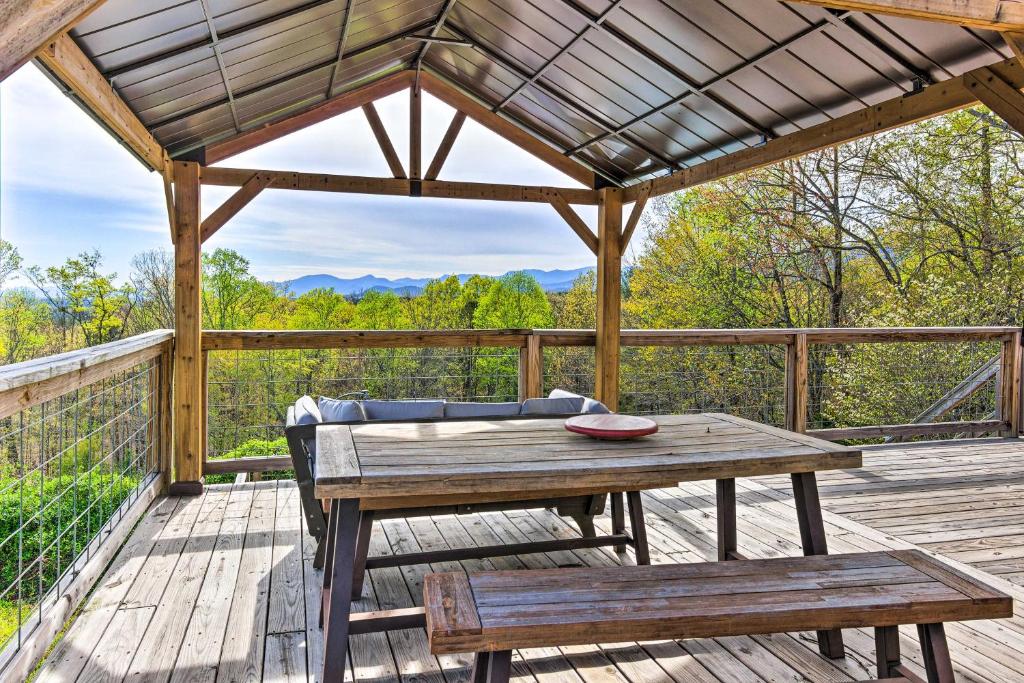 eine Holzterrasse mit einem Tisch und Bänken auf einem Dach in der Unterkunft Amenity-Packed Nebo Oasis with Deck and Mtn Views in Nebo