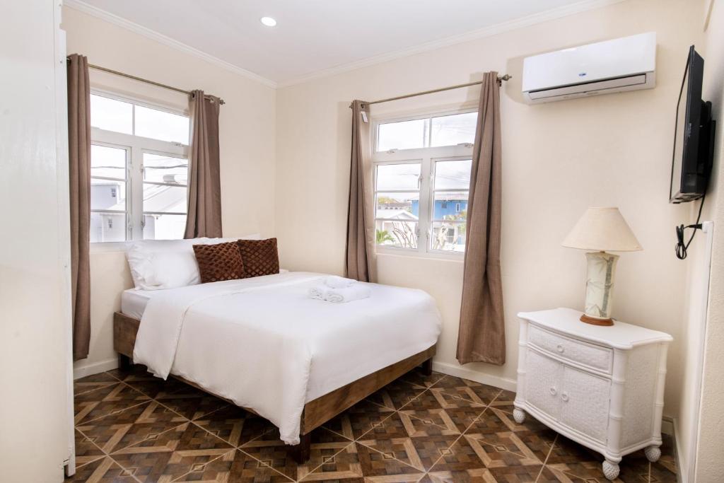 a bedroom with a white bed and two windows at Mariner Suites in Christ Church