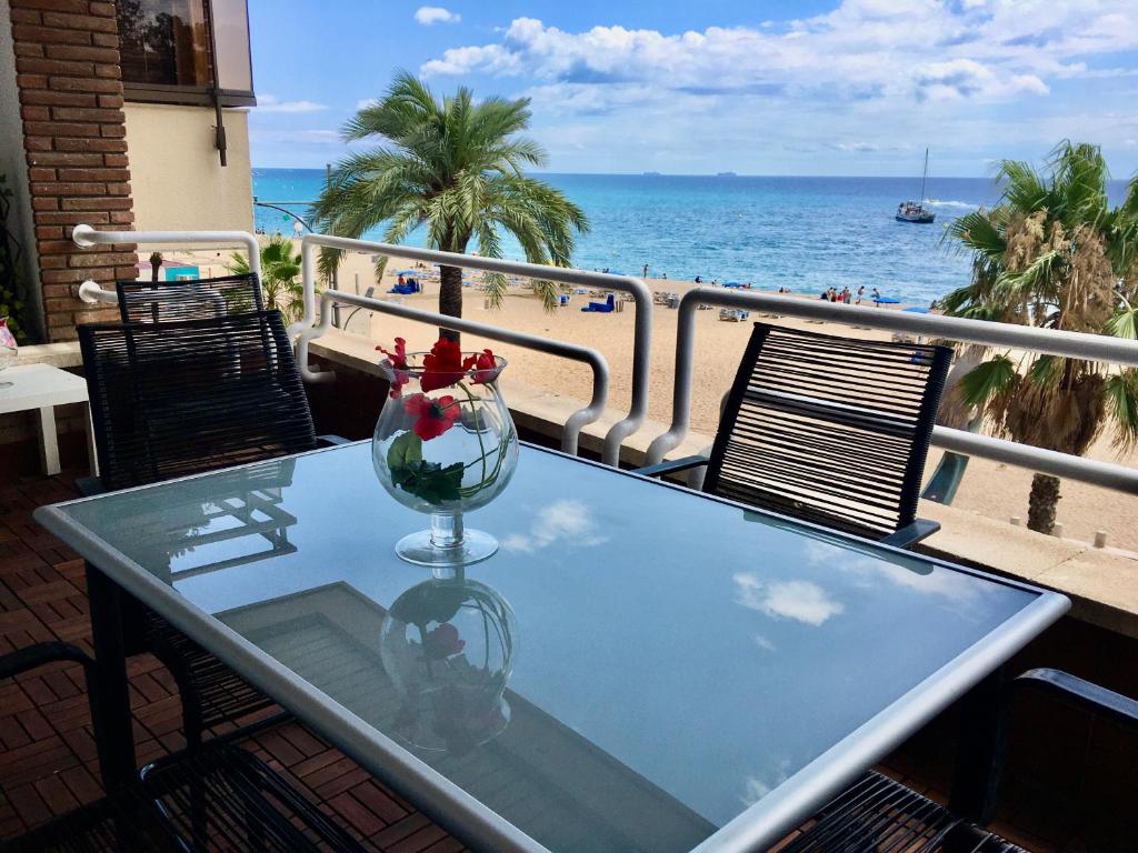 une table en verre avec un vase de fleurs sur le balcon dans l'établissement Vivalidays Rosalia - LLoret de Mar centro, à Lloret de Mar