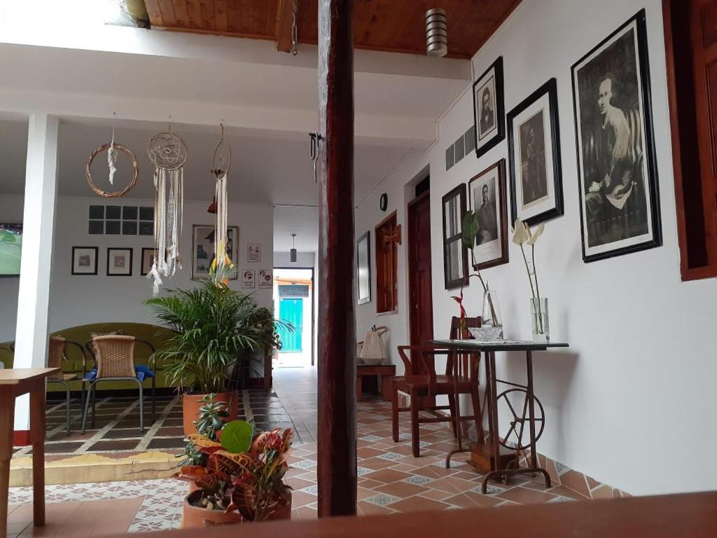 Hostal La Comedia في خاردين: غرفة معيشة مع طاولة وبعض الصور على الحائط