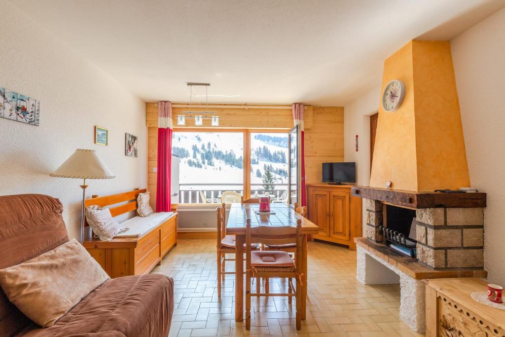 uma sala de estar com uma mesa e uma lareira em Apartment with Balcony and View em Le Grand-Bornand