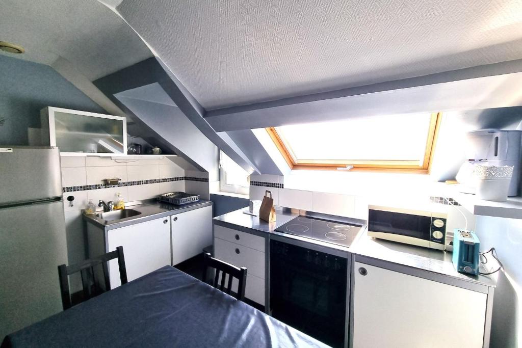 uma pequena cozinha com armários brancos e uma janela em Peaceful Apt At 2 Steps From The Beach em Luc-sur-Mer