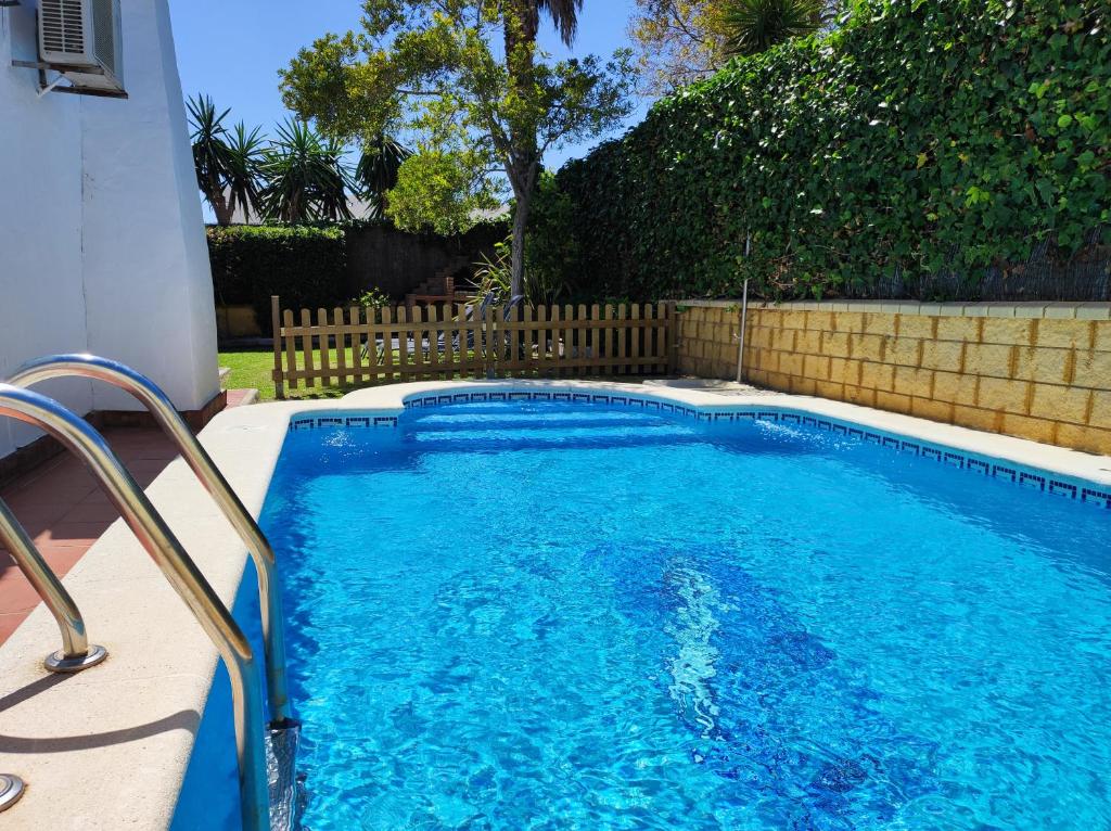 ein kleiner Pool in einem Garten mit einem Zaun in der Unterkunft Casa Juanse in Conil de la Frontera