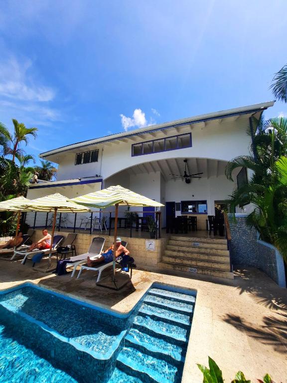 a man sitting in a chair next to a swimming pool at Villa Roca Boutique Resort & Suites - ADULT ONLY in Manuel Antonio