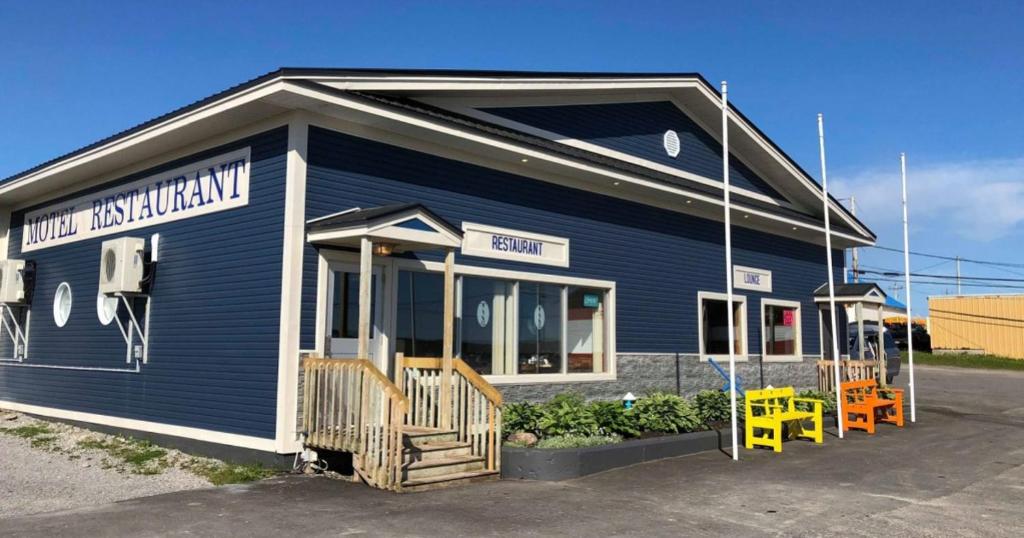 un edificio azul con sillas amarillas delante en Sea Echo Motel, en Port au Choix