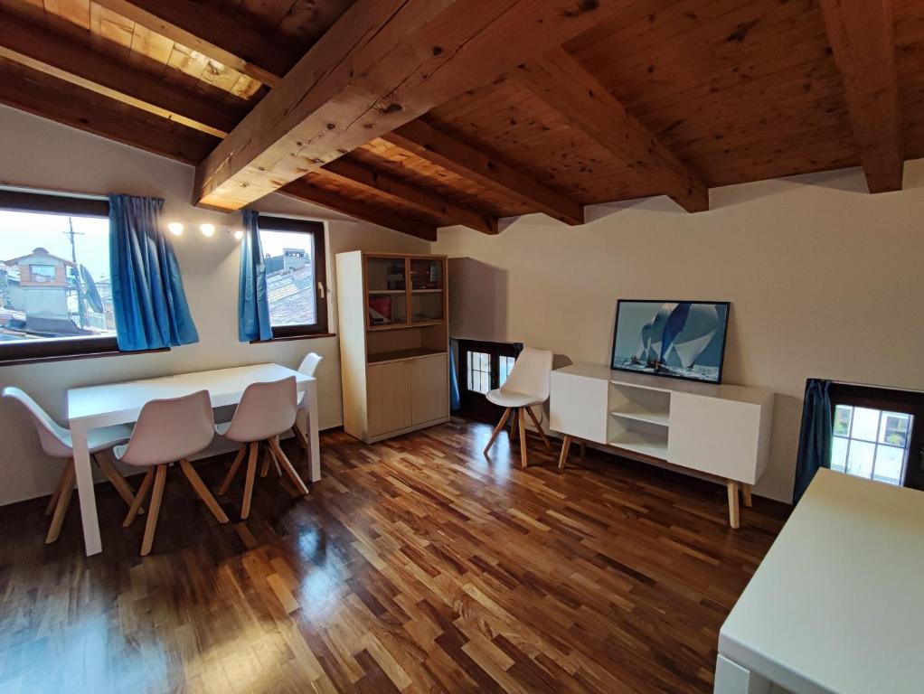 sala de estar con mesa, sillas y TV en Al Lago Apartments, en Riva del Garda