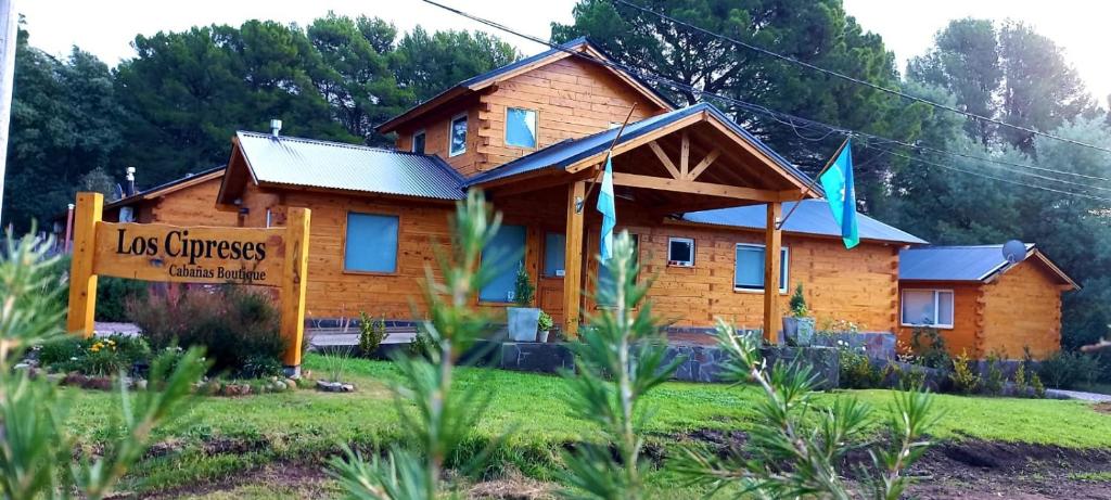 een houten huis met een bord ervoor bij Cabañas Boutique Los Cipreses in Villa Ventana