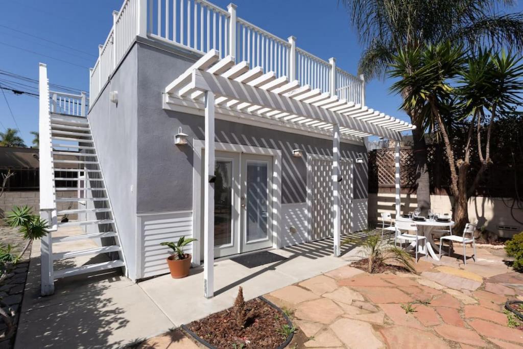 a white house with a staircase and a patio at North Park Studio Bungalow in San Diego
