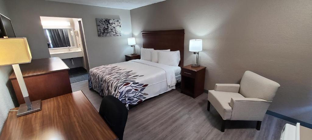 a hotel room with a bed and a chair at Red Roof Inn LaGrange in La Grange