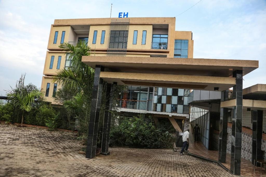 Un bâtiment avec un homme debout devant lui dans l'établissement Easternhillshotels&Spa, à Kigali