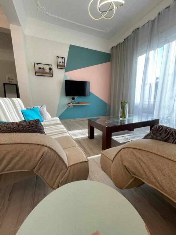 ein Wohnzimmer mit 2 Betten und einem Tisch in der Unterkunft Central Number 10 in Néa Péramos