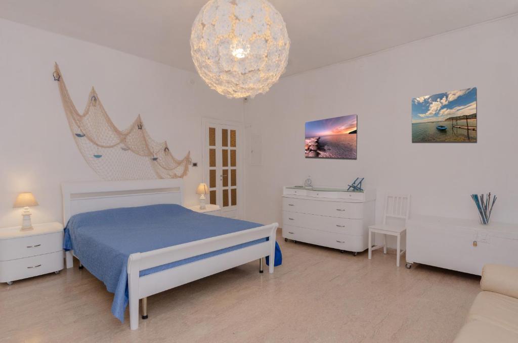 a white bedroom with a blue bed and a chandelier at Da zio Antonio in Vieste