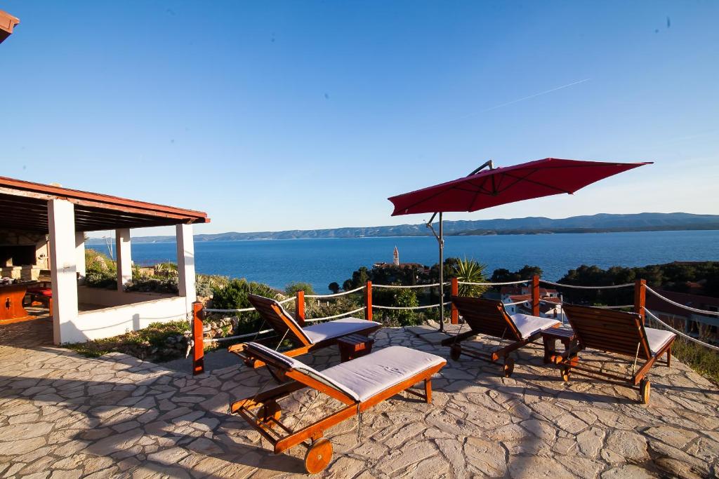 a patio with chairs and an umbrella next to the water at Holiday Home Baki in Bol